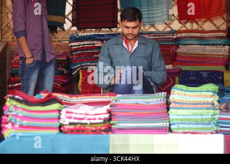 Auf einer Messe in Delhi, Indien, zeigen die Händler traditionelle indische Kleidung und Textilien. Stockfoto