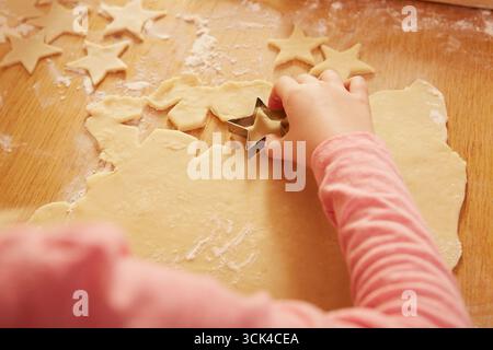 Mädchen schneiden sternförmige Kekse aus Keksteig Stockfoto