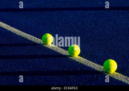 Gelbe Padelkugeln mit langen dramatischen Schatten, Abendlicht Stockfoto