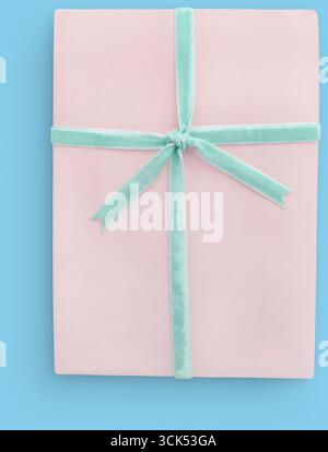 Eine wunderschön verpackte, pinkfarbene Geschenkbox mit einem mintgrünen Band, perfekt für Feiern oder besondere Anlässe. Stockfoto