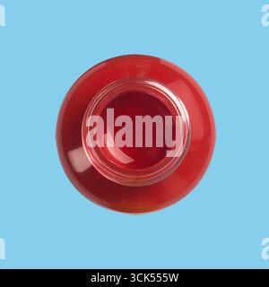 Ein Blick von oben auf eine rote nagellackflasche mit glänzendem Finish und offenem Verschluss. Stockfoto