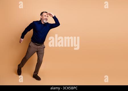 Ein selbstbewusster Geschäftsmann posiert in formeller Kleidung vor beigefarbenem Hintergrund dynamisch und verkörpert Professionalität und Stil Stockfoto