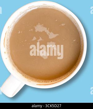Ein Blick von oben auf eine Tasse, die mit brauner Flüssigkeit gefüllt ist, wahrscheinlich mit Kaffee oder Tee, und die cremige Textur zeigt. Stockfoto