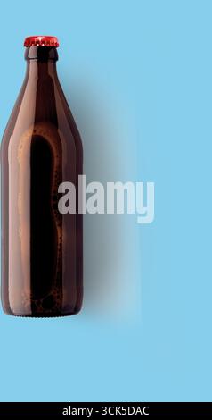 Eine dunkle Glasflasche mit rotem Verschluss, die möglicherweise ein Getränk enthält, vor einem hellen Hintergrund. Stockfoto