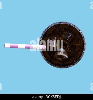 A top-down view of a glass filled with dark fizzy drink and ice cubes, featuring a striped straw. Stockfoto