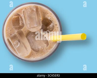 Ein erfrischendes Eisgetränk in einer Tasse mit Eiswürfeln und gelbem Strohhalm. Stockfoto