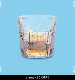 Ein mit Whiskey gefülltes Kristallglas mit sattem Bernstein und einem einzigen Eiswürfel. Stockfoto