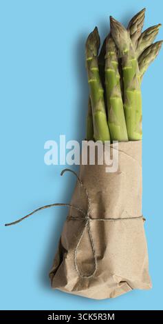 Ein Bündel frischer Spargel, in braunes Papier gewickelt, mit Garn gebunden, um seine leuchtende grüne Farbe und seine natürliche Erscheinung zu zeigen. Stockfoto