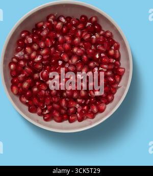 Eine Schüssel gefüllt mit leuchtenden roten Granatapfelkernen, die ihre saftige Textur und satte Farbe zeigen. Stockfoto