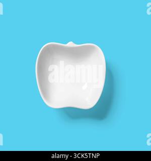 Eine weiße Keramikschale in Form eines Apfels, geeignet zum Servieren von Snacks oder zu dekorativen Zwecken. Stockfoto