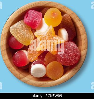 Eine lebendige Auswahl an Bonbons aus Gummi in einer Holzschale, die verschiedene Formen und Farben zum Genuss bietet. Stockfoto