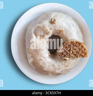 Ein köstlicher Donut mit Glasur und einem Stück Waffel, serviert auf einem weißen Teller. Stockfoto