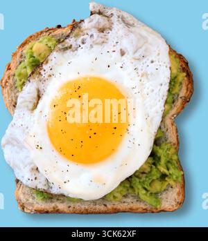 Eine Scheibe geröstetes Brot, garniert mit Avocado-Püree und einem Ei mit der sonnigen Seite nach oben, garniert mit schwarzem Pfeffer. Stockfoto