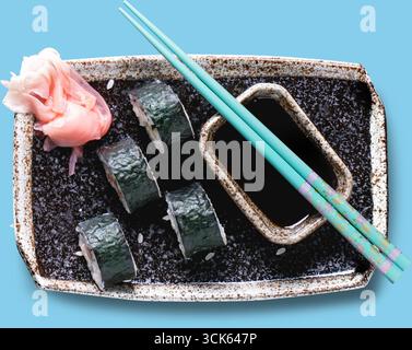Eine Sushi-Platte mit Brötchen, eingelegtem Ingwer und Sojasauce, serviert mit Essstäbchen, die japanische Küche hervorheben. Stockfoto