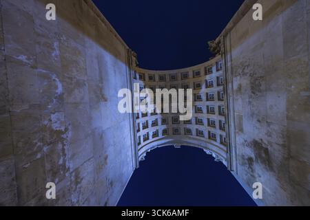 Blick durch eine hohe Arkade in den Nachthimmel mit Gitterstruktur, Siegestor, München, Deutschland Stockfoto