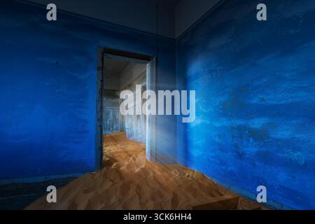 Nachmittagslicht kostet durch das verlassene Haus mit blauem Wandraum in Kolmanskop bei Sonnenuntergang, verlassenes Diamantenminendorf im Süden Namibias. Stockfoto