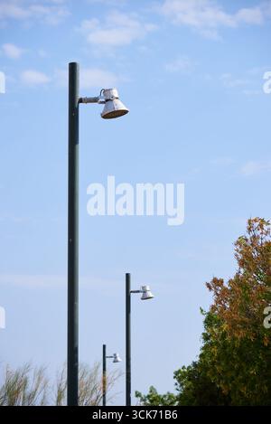 Straßenlaternen in einem öffentlichen Park mit blauem Himmel und Wolken in Spanien Stockfoto