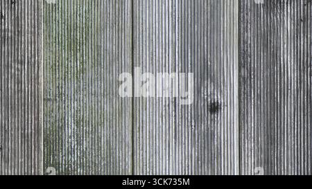 Eine Nahaufnahme verwitterter Holzdielen mit unterschiedlichen Grau- und Grüntönen, die Textur und Alterung zeigen. Stockfoto