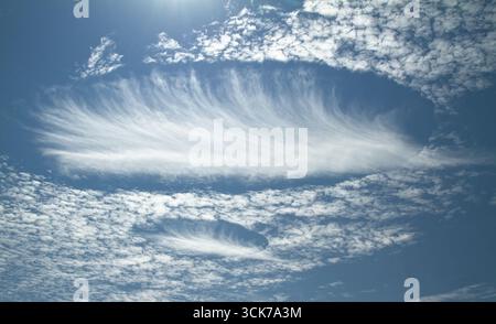 Ein Paar seltener elliptischer Fallstriak-Loch-Wolken im Himmel über dem Süden Englands, das durch Verdampfen von unterkühltem Wasser verursacht wird, manchmal verwirrtes W Stockfoto