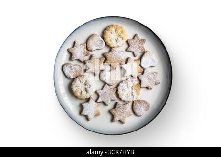 Ein Teller mit verschiedenen Sternen- und Herzkeksen, mit Puderzucker bestäubt. Stockfoto