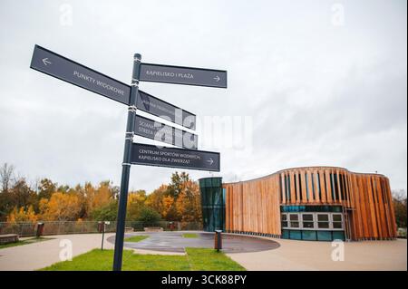 Modernes Holzgebäude mit Richtungsschildern in Parklage. Stockfoto