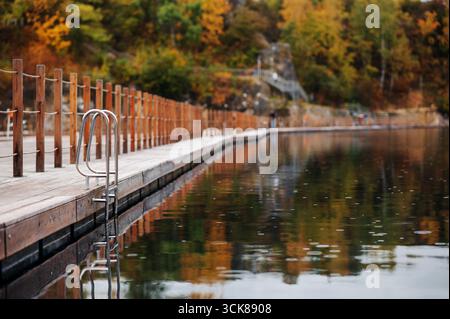 Eine ruhige Strandpromenade am See mit Herbstlaub, das sich im Wasser spiegelt. Steinbruch Zakrzówek, Krakau Stockfoto