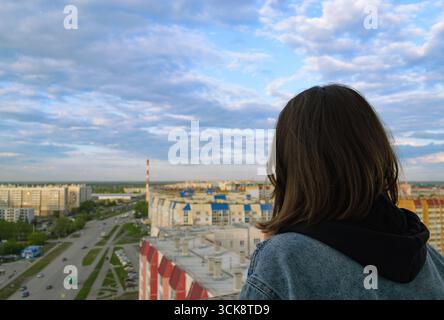 Foto von hinten von einem Mädchen, das aus der Höhe auf die Stadt blickt Stockfoto