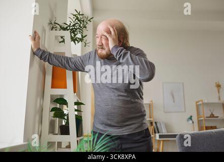 Schwindliger älterer Mann, der mit der Hand auf der Stirn steht und Beschwerden durch Schwindel oder Kopfschmerzen hat. Stockfoto