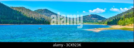 Panorama Lake Boot und bewaldete Hügel unter blauem Himmel Stockfoto