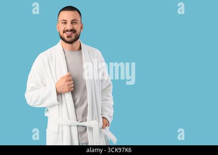Lächelnder junger Mann im Gewand auf blauem Hintergrund Stockfoto