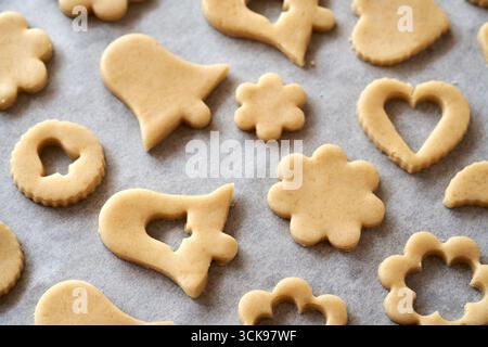 Formen, die auf einem Blatt Backpapier aus dem Teig ausgeschnitten wurden - Zubereitung von Lebkuchen-Weihnachtskeksen Stockfoto