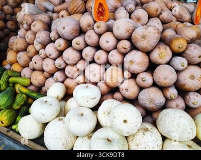 Eine lebendige Ausstellung mit verschiedenen Kürbiss und Kürbissen in verschiedenen Formen, Größen und Farben, die in den Regalen in der Lebensmittelabteilung des Geschäfts angeordnet sind Stockfoto