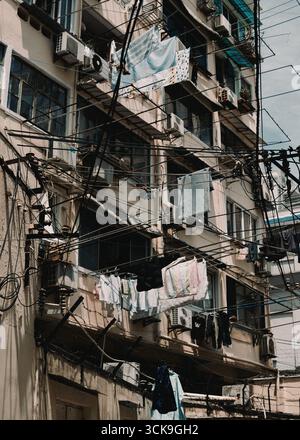 Altes Apartmentgebäude mit Wäsche, die draußen hängt und verworrene Freileitungen in Shanghai Stockfoto
