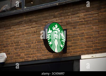Starbucks Coffee Shop Schild an einer Backsteinmauer in einer städtischen Straße, bei Tageslicht fotografiert. Nur redaktionelle Verwendung. Stockfoto