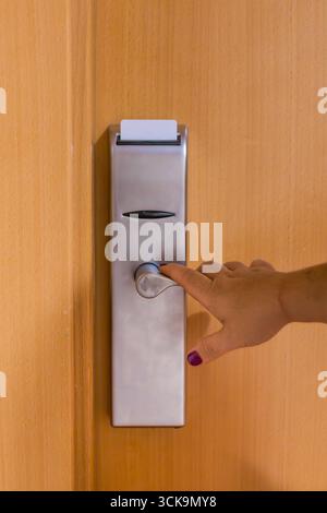 Die Hand der Frau steckt eine Schlüsselkarte in die Tür des Hotelzimmers und öffnet den Zugang zu einer gemütlichen Einrichtung, perfekt für Reisen und Entspannung Stockfoto