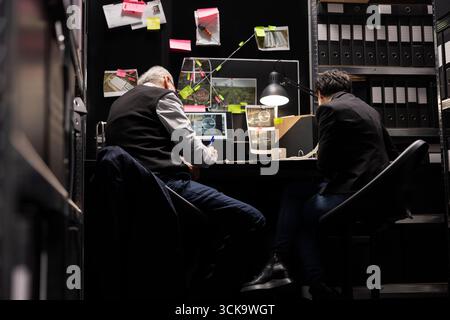 Detektivteam analysiert Akten und Dokumente, um Verbindungen zwischen Verdächtigen in einem Vorfallsraum für laufende strafrechtliche Ermittlungen aufzudecken. Beweisauslegung für eine Mission. Stockfoto