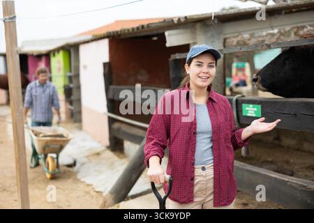 Porträt einer lächelnden jungen Bauernfrau im Garten des Bauernhofs beim Putzen Stockfoto
