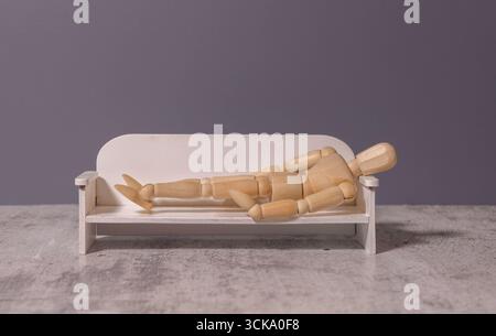 Eine junge Frau liegt auf einer Couch beim Termin eines Psychologen. Ein brauner, männlicher Psychologe mit Brille führt eine psychologische Sitzung durch Stockfoto