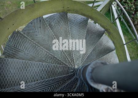 Draufsicht auf die industrielle Wendeltreppe mit strukturierten Metallstufen und geometrischen Mustern. Stockfoto