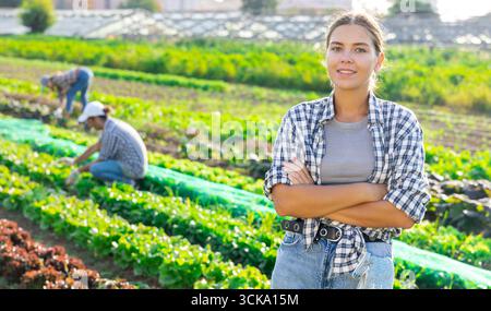Porträt junger glücklicher Hofbesitzer vor dem Hintergrund des Feldes mit Gemüseernte Stockfoto