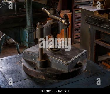 Monroe, NY - USA - 6. September 2025 Nahaufnahme einer antiken Eisenbücherpresse und dazugehörigen Ausrüstung in der Druckerei im Museum Village, in der traditionelle Produkte gezeigt werden Stockfoto