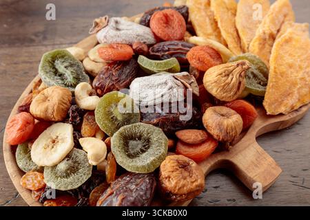 Getrocknete Mangoblätter, tropische Früchte, Nüsse und Rosinen auf einem alten Holztisch. Draufsicht. Stockfoto