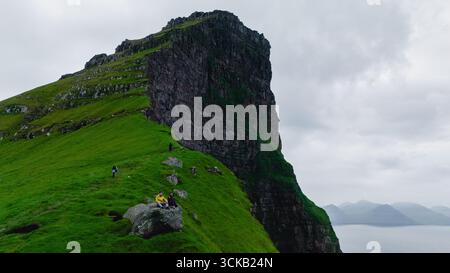 Majestätische Klippen erheben sich dramatisch inmitten üppiger Grünflächen auf den bezaubernden Färöer Inseln. Kallur Leuchtturm Kalsoy Island Stockfoto