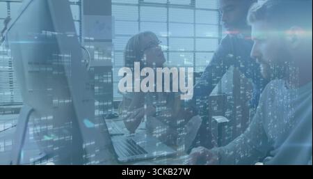 Kooperierende Experten prüfen Daten auf Monitor und Laptop im Büro mit Code-Overlay Stockfoto