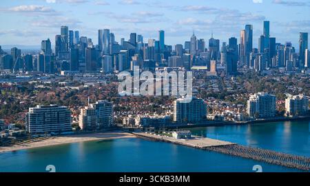 Blick über den Strand von Port Melbourne und den Pier in Richtung der Skyline im Zentrum von Melbourne bei Tageslicht Stockfoto