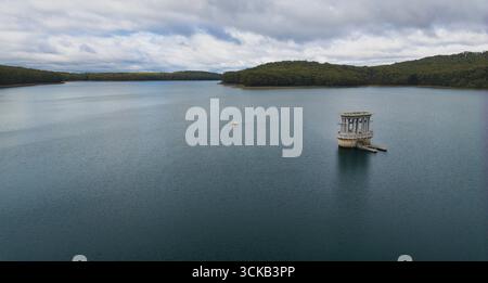 Der Einlassturm am Silvan Reservoir liegt isoliert in ruhigem Wasser in der Nähe bewaldeter Hügel Stockfoto
