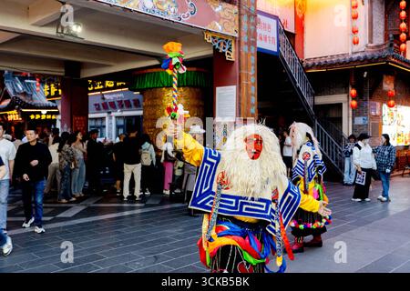 Ein tibetischer Operndarsteller in traditioneller Maske und Tracht unterhält die Menge in der berühmten Stadt Liu Liu in Kangding während der Abenddämmerung. Stockfoto