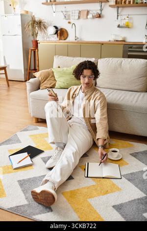 Ein junger Mann in Business-Mode sitzt bequem auf dem Boden und schreibt Ideen. Stockfoto