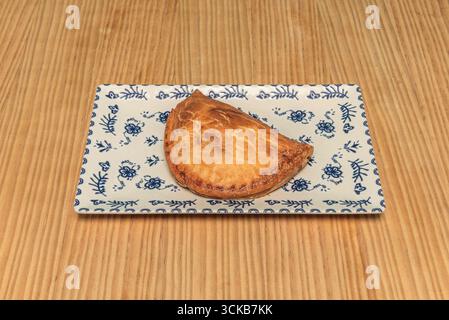 Empanadas mit Kartoffeln und Würstchen, rustikales Gebäck, in einem Tontopf mit Paprika präsentiert Stockfoto