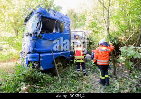 Pattensen, Deutschland. September 2025. Feuerwehrleute stehen neben einem Lkw, der an einem Unfall beteiligt war, auf der Bundesautobahn B3 im Raum Hannover. Der Lkw hatte die B3 am Morgen verlassen und die entgegenkommende Spur überquert und dabei mehrere Bäume getroffen. Quelle: Julian Stratenschulte/dpa - ACHTUNG: Firmenname wurde aus rechtlichen Gründen pixeliert/dpa/Alamy Live News Stockfoto